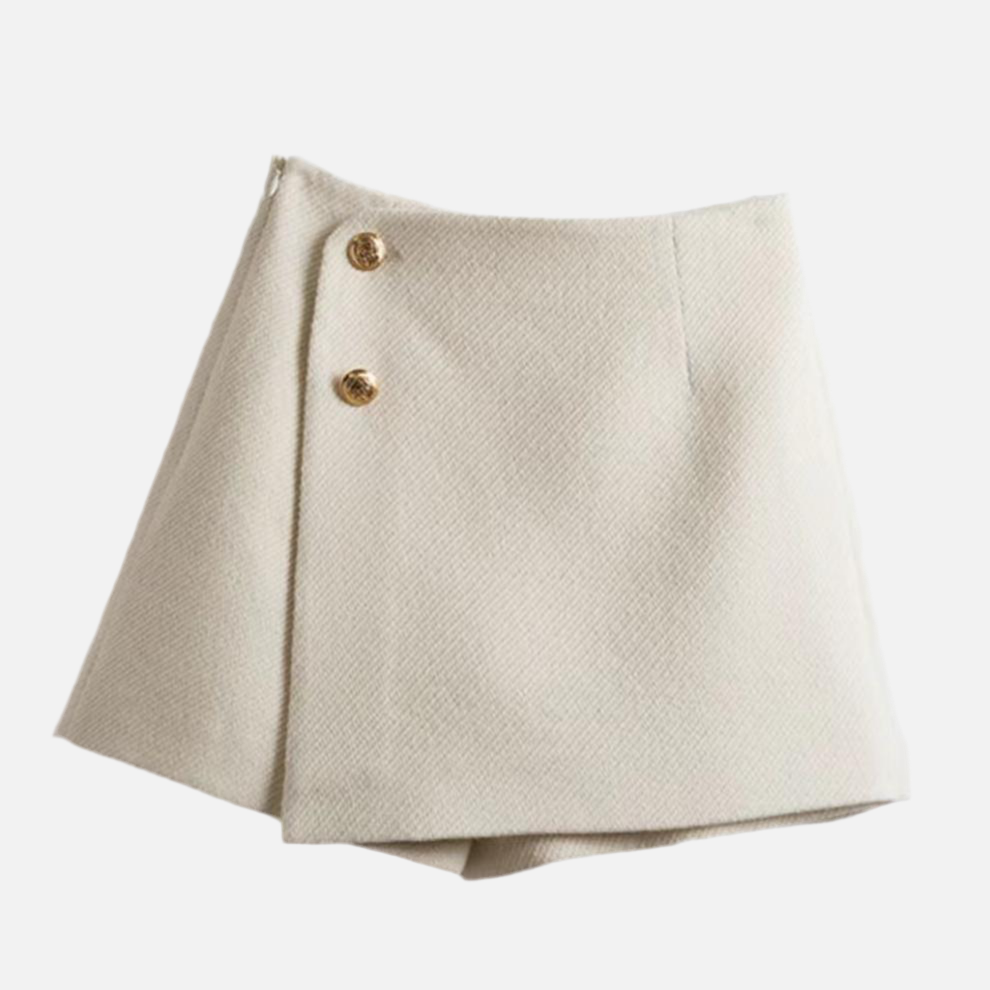 Short saia Gabby em tweed, com botões dourados, cintura alta e modelagem estruturada. Elegante e moderno. Disponível do P ao GG, em off-white e preto.

